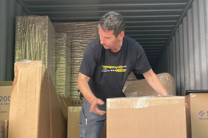 umzugshelfer verpackt umzugskarton im container